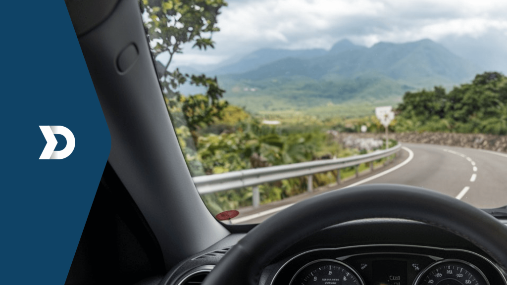 View from the driver's seat of a car on a scenic mountain road with lush greenery and winding curves.
