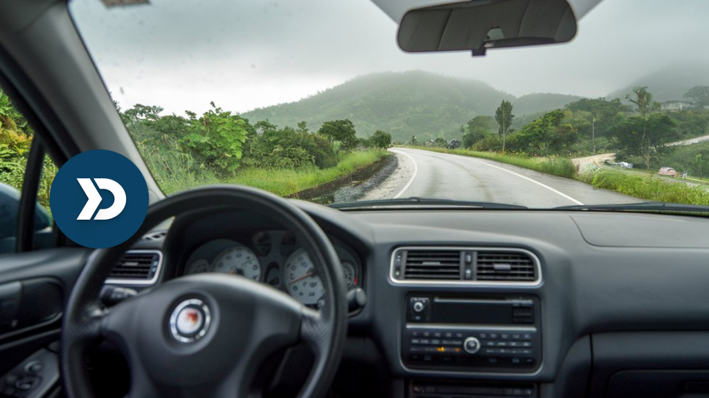 A car dashboard view of a scenic winding road through lush green hills, symbolizing the role of mobile telematics in promoting safe and distraction-free driving.