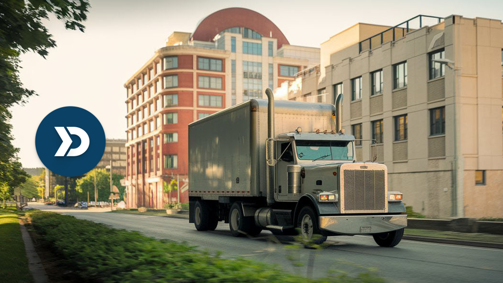 A silver semi-truck drives through a city street lined with mid-rise buildings, symbolizing mobile telematics in urban logistics and raising ethical questions about data usage.